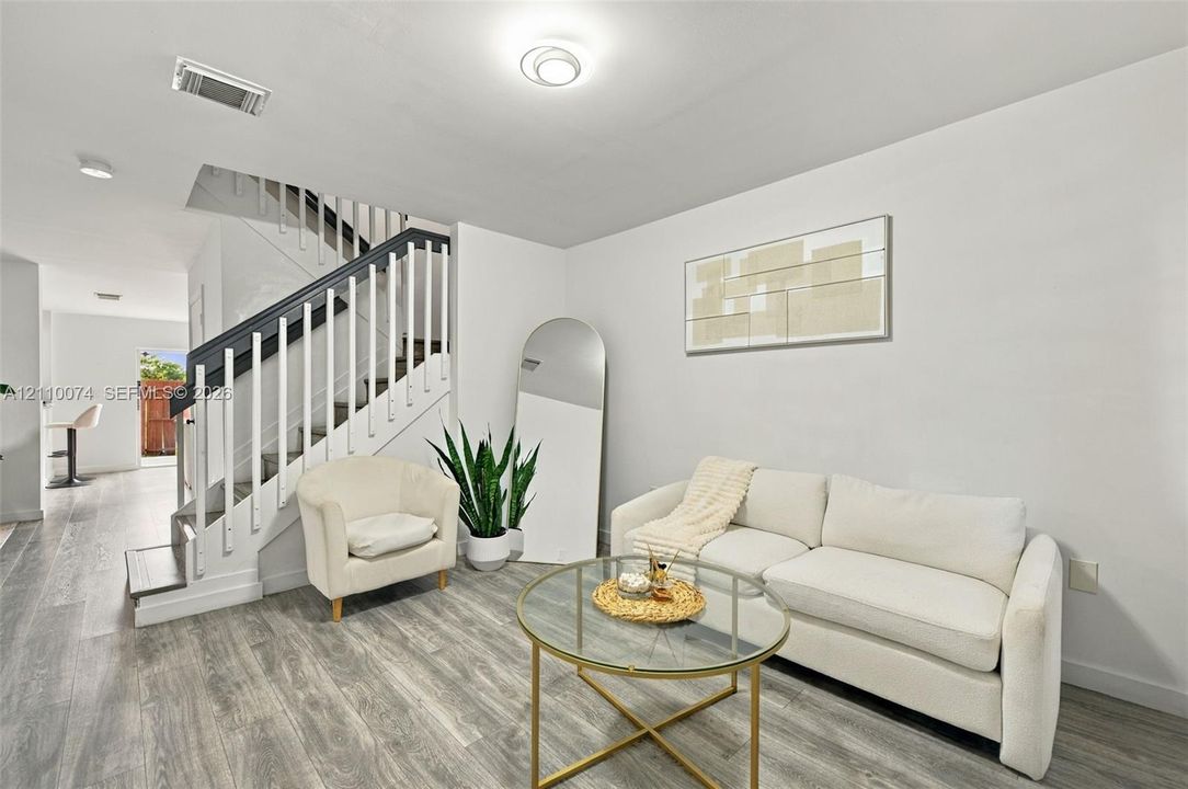 Staircase featuring white balusters with dark-toned handrails, wood-finish flooring, and recessed ceiling lighting