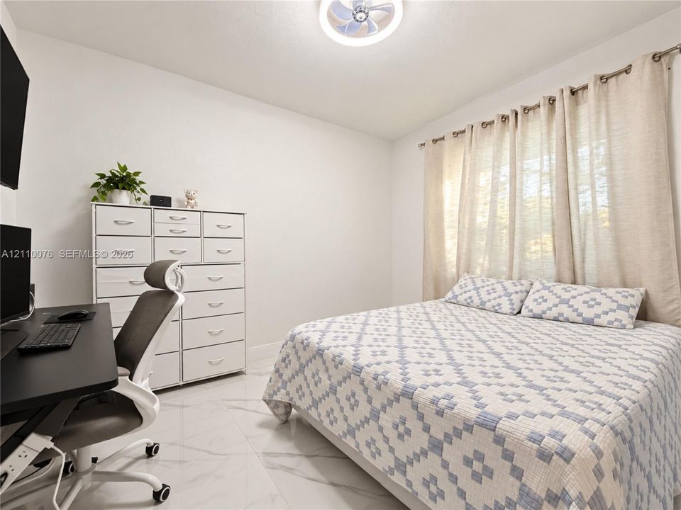 Large-format polished tile flooring, neutral wall palette, and a central ceiling-mounted LED fan fixture