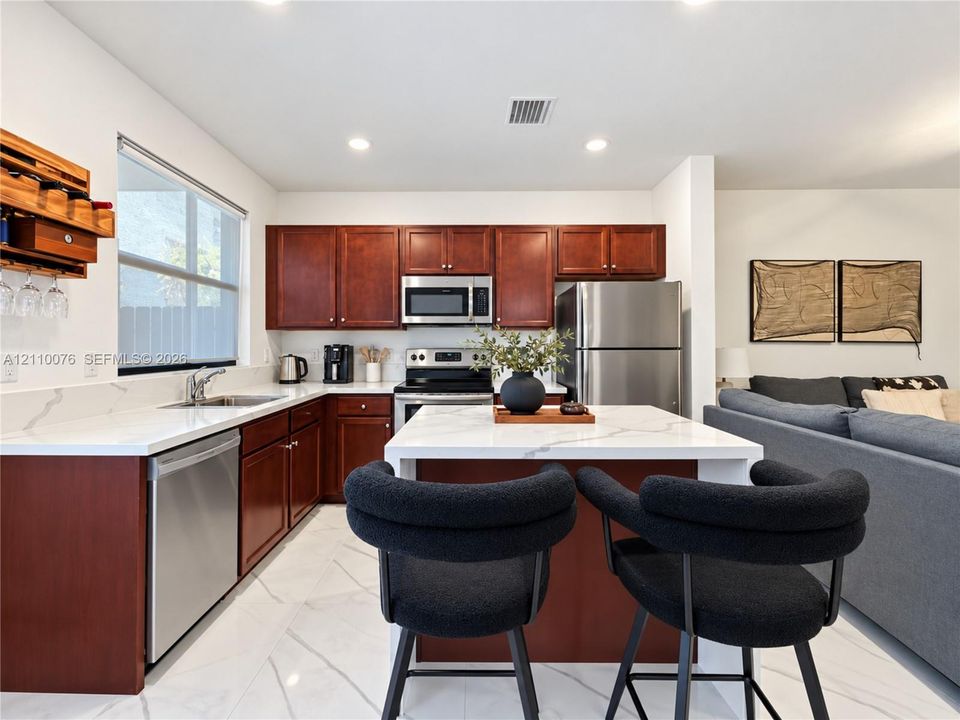 Kitchen featuring dark wood cabinetry, a central island with a stone-surface countertop, stainless steel appliances, and large-format tile flooring