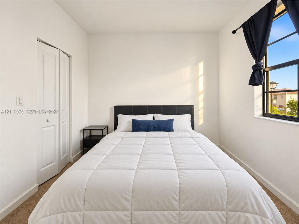 Room featuring neutral wall paint, carpeting, a multi-pane window with a black frame, and a closet with a white paneled bifold door