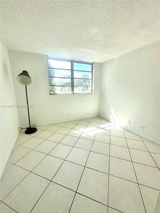 Room featuring neutral ceramic tile flooring laid in a diagonal pattern and a multi-pane horizontal sliding window