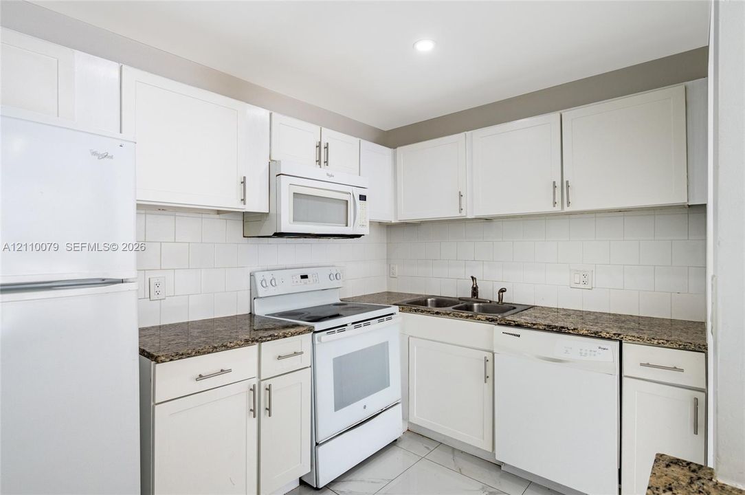 Kitchen featuring white cabinetry, stone-finish countertops, subway tile backsplash, white appliances, and tiled flooring
