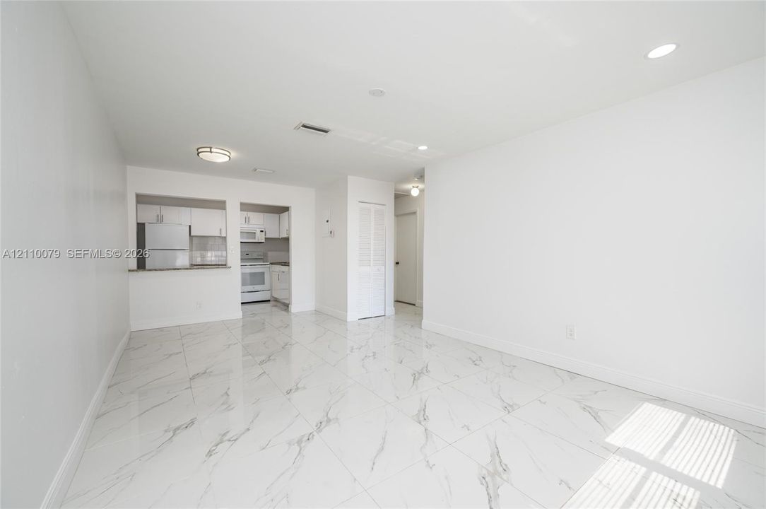 Large-format tile flooring with veining, white cabinetry, integrated pass-through, recessed lighting, and flush-mount ceiling fixture