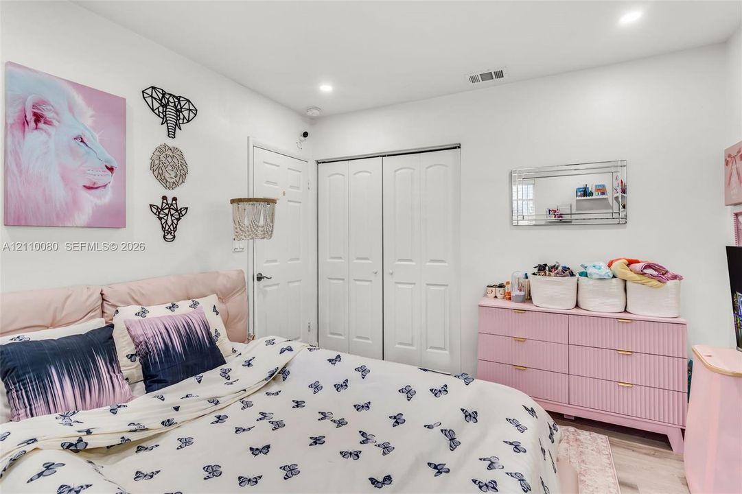 Bedroom featuring recessed lighting, a double-door closet with paneled detailing, and wood-finish flooring