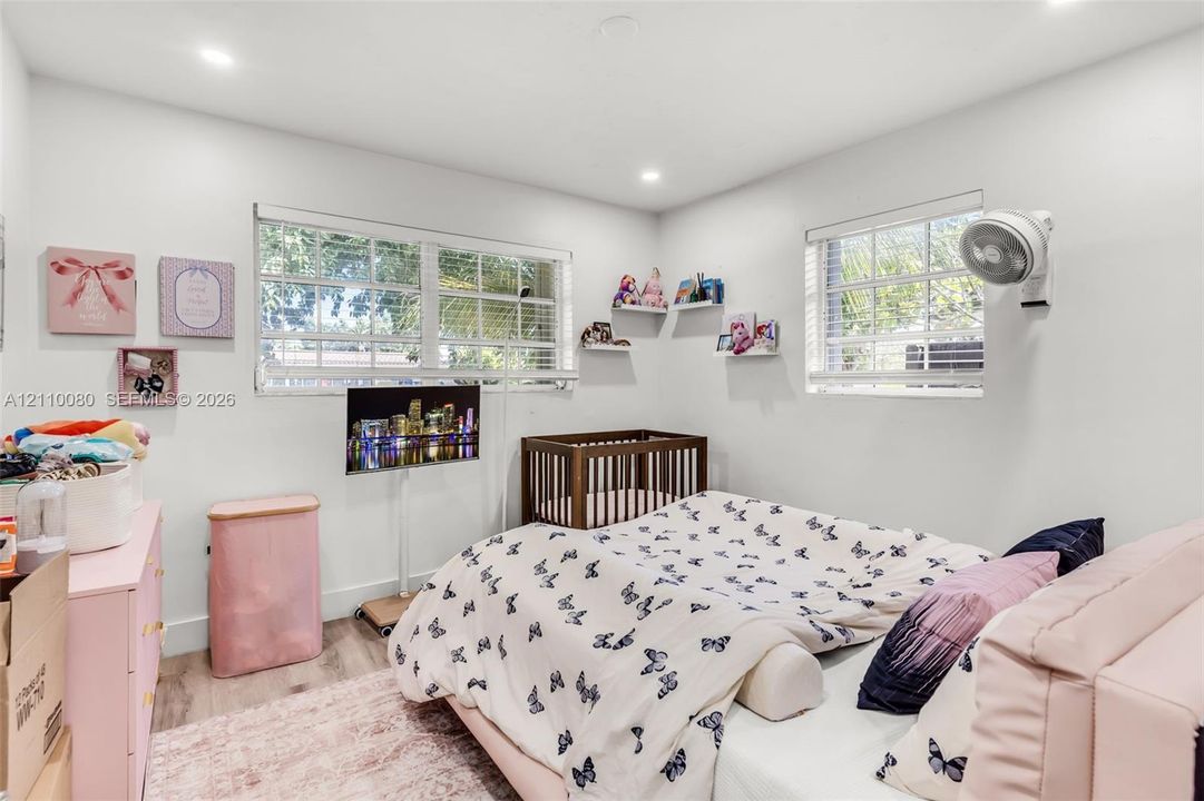 Room featuring wood-finish flooring, dual windows with blinds, recessed lighting, and built-in floating wall shelves