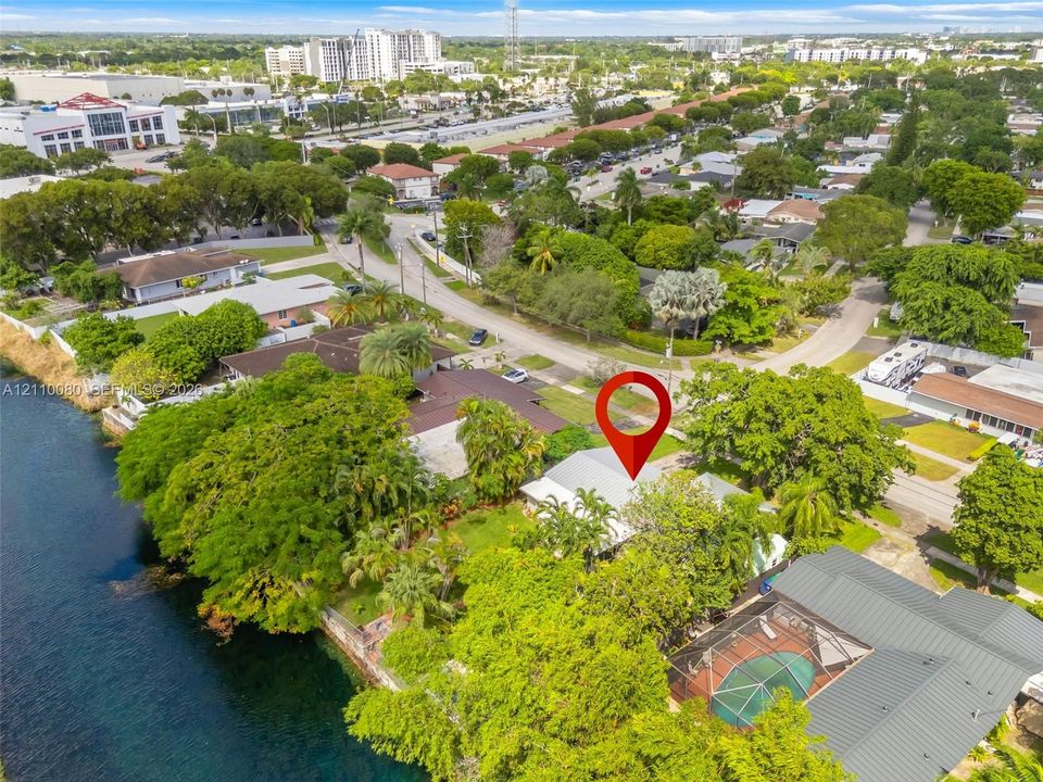 Waterfront property featuring direct canal access, mature trees, and an enclosed screened-in pool area