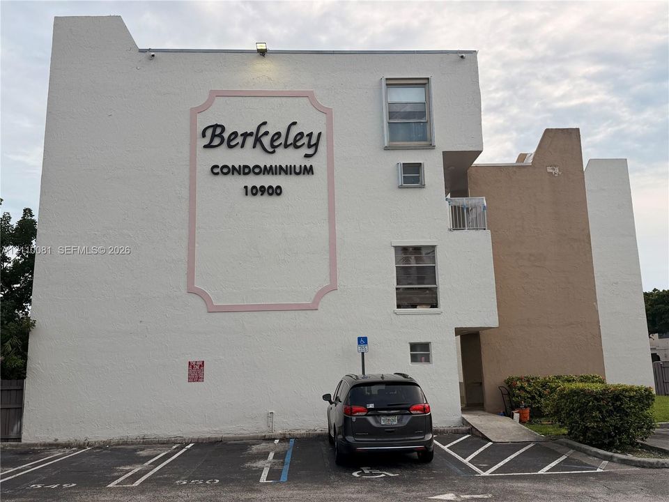 Exterior facade featuring a stucco finish, multi-level building design, dedicated parking stalls, and paved access ramp