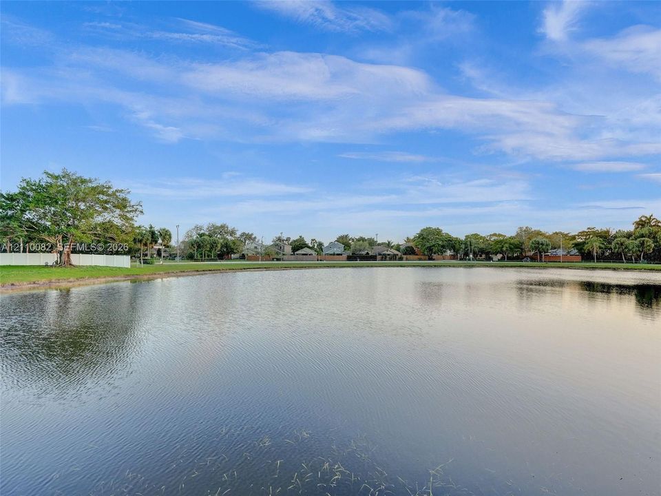 Waterfront lot featuring a wide expanse of open water, manicured grass perimeter, and mature trees