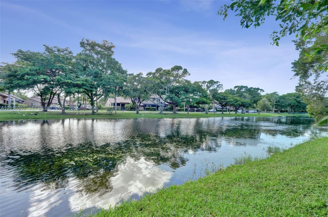 Waterfront property featuring a canal, expansive lawn, and mature trees
