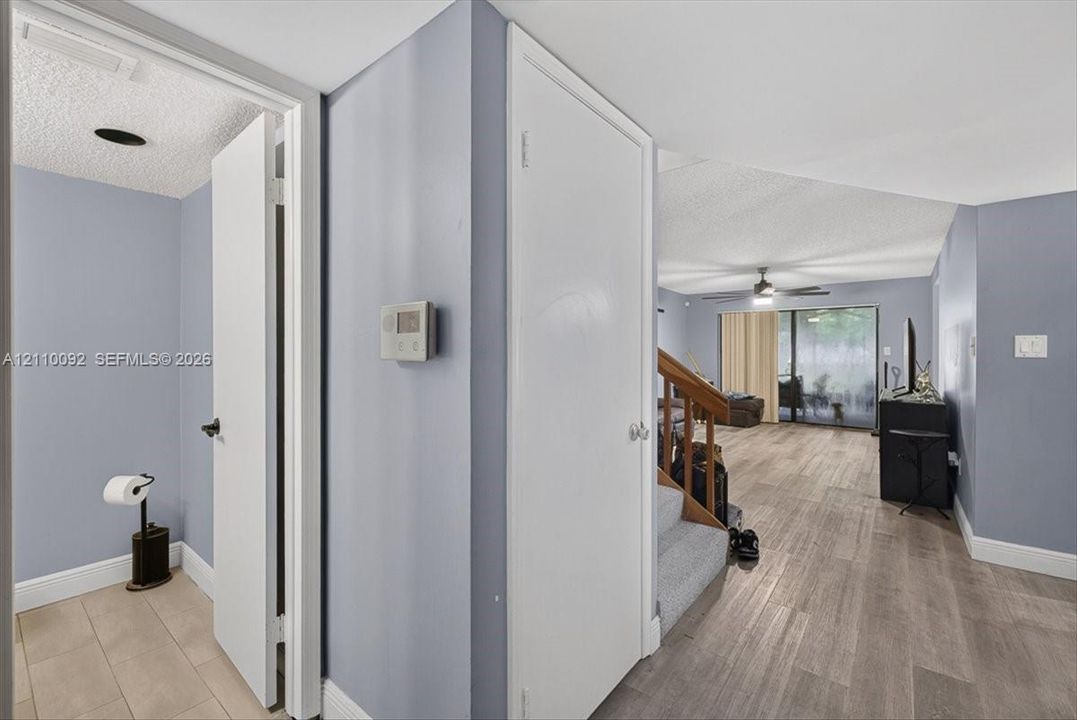 Interior hall featuring wood-finish flooring, staircase with carpeted treads and wooden handrail, and sliding glass door