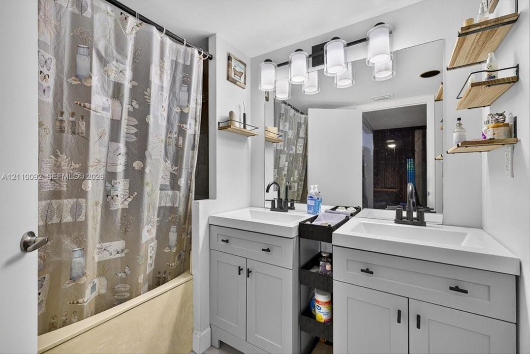 Double vanity featuring gray Shaker-style cabinetry, white integrated rectangular sinks, matte black faucets, and a five-light vanity fixture