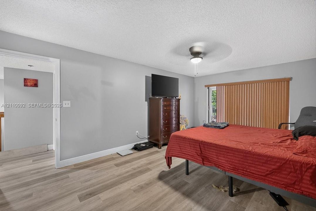 Wood-finish flooring, ceiling fan with integrated lighting, and vertical window blinds
