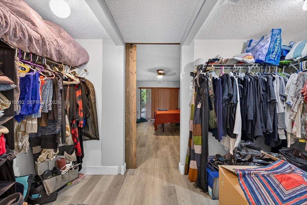 Walk-in storage space featuring built-in wire shelving, wood-finish flooring, and a rustic wood-trimmed doorway