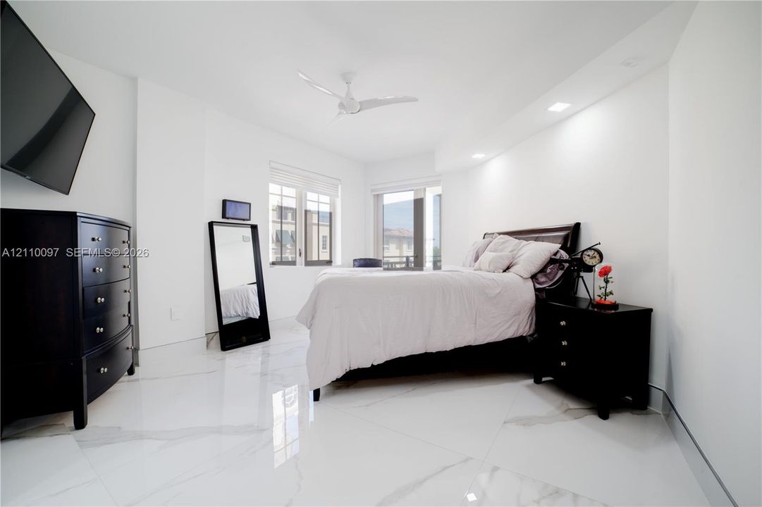 Large-format stone tile flooring, recessed ceiling lighting, and a white multi-blade ceiling fan