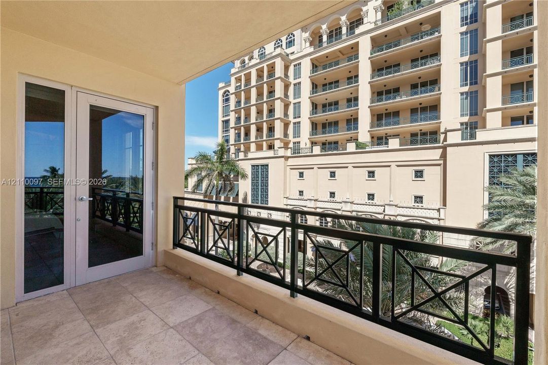 Covered balcony featuring stone tile flooring and a black metal geometric railing