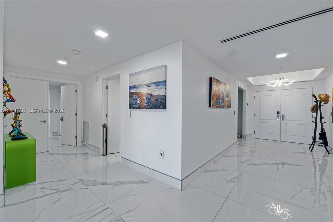 Foyer featuring large-format veined tile flooring, recessed ceiling lighting, a tray ceiling detail, and double-entry doors