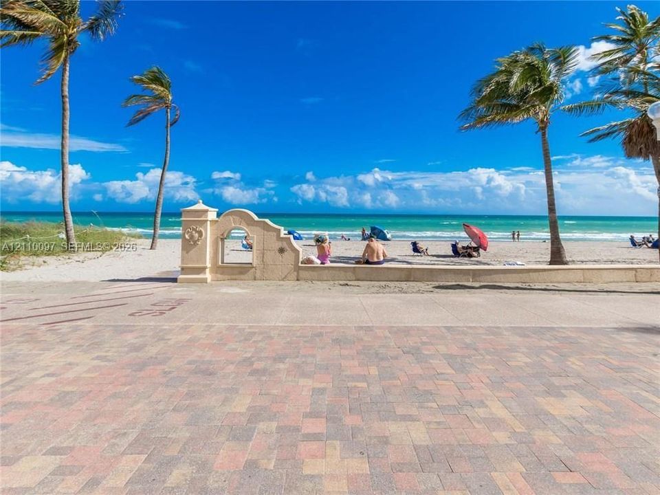 Brick-paver patio featuring a decorative stone archway, perimeter wall, and mature palm trees