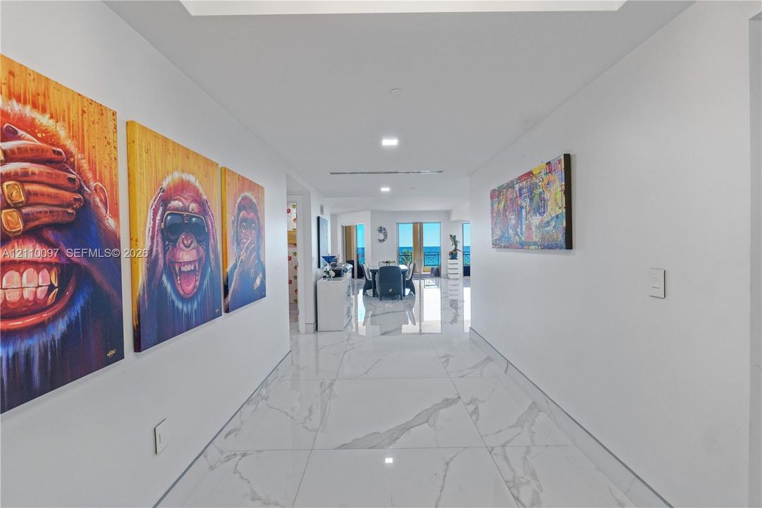 Large-format stone-finish floor tiling, recessed ceiling lighting, and expansive glass doors offering ocean exposure