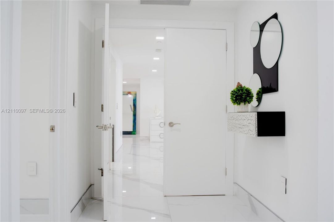 Interior hallway featuring large-format white veined flooring and recessed ceiling lighting