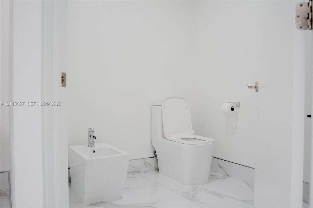 Freestanding soaking tub with a wall-mounted chrome hand shower and faucet assembly, accented by a decorative navy and white geometric tiled wall