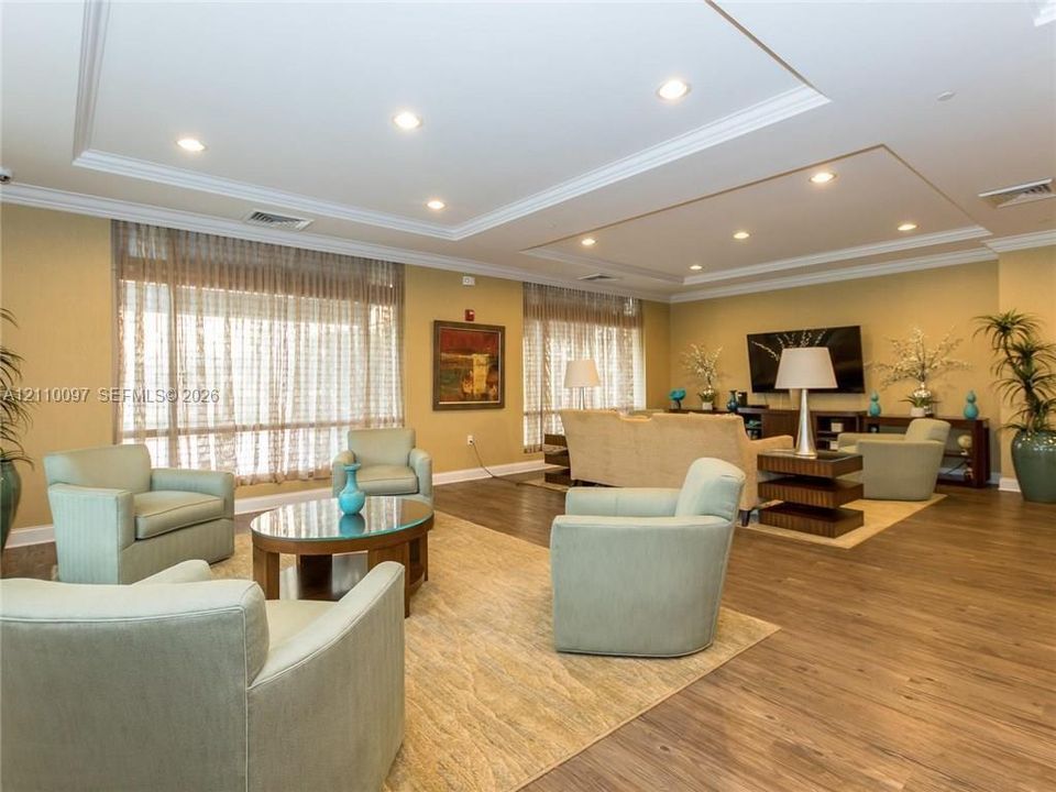 Spacious interior featuring wood-finish flooring, recessed lighting, crown molding, and large windows with integrated window treatments