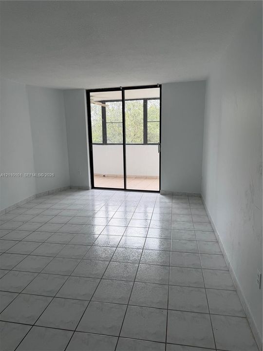Interior space featuring large-format tile flooring and floor-to-ceiling sliding glass doors leading to a covered balcony