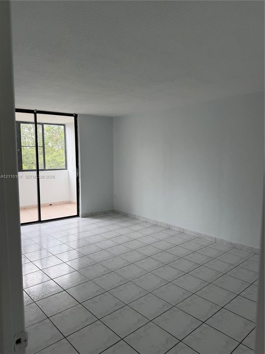 Interior space featuring ceramic tile flooring, neutral walls, and large glass sliding doors providing exterior access