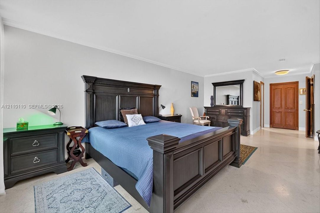 Spacious room featuring neutral wall tones, large-format stone-finish flooring, and solid wood double-panel doors