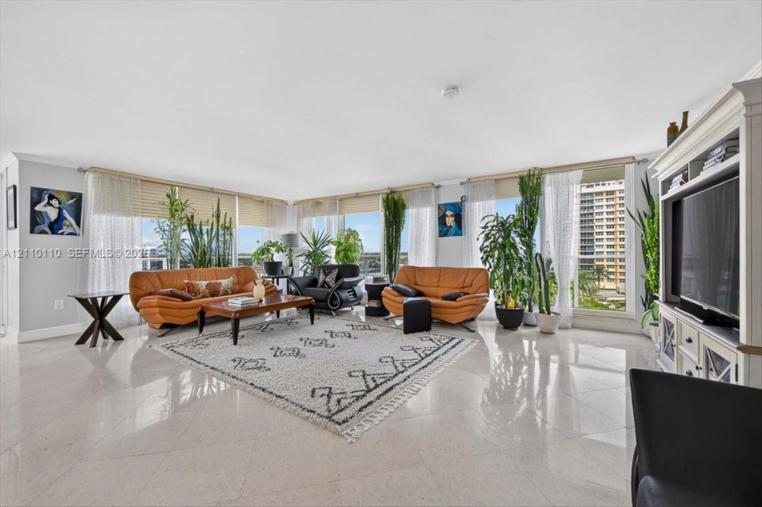 Expansive living area featuring large-format tile flooring, floor-to-ceiling windows, and custom built-in entertainment cabinetry