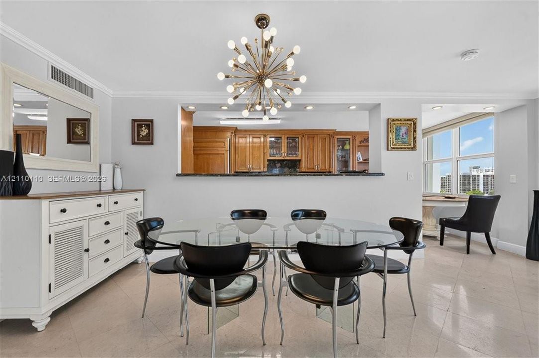 Dining area featuring a modern sputnik-style chandelier, tile flooring, crown molding, a built-in kitchen pass-through window with a stone countertop, and large windows