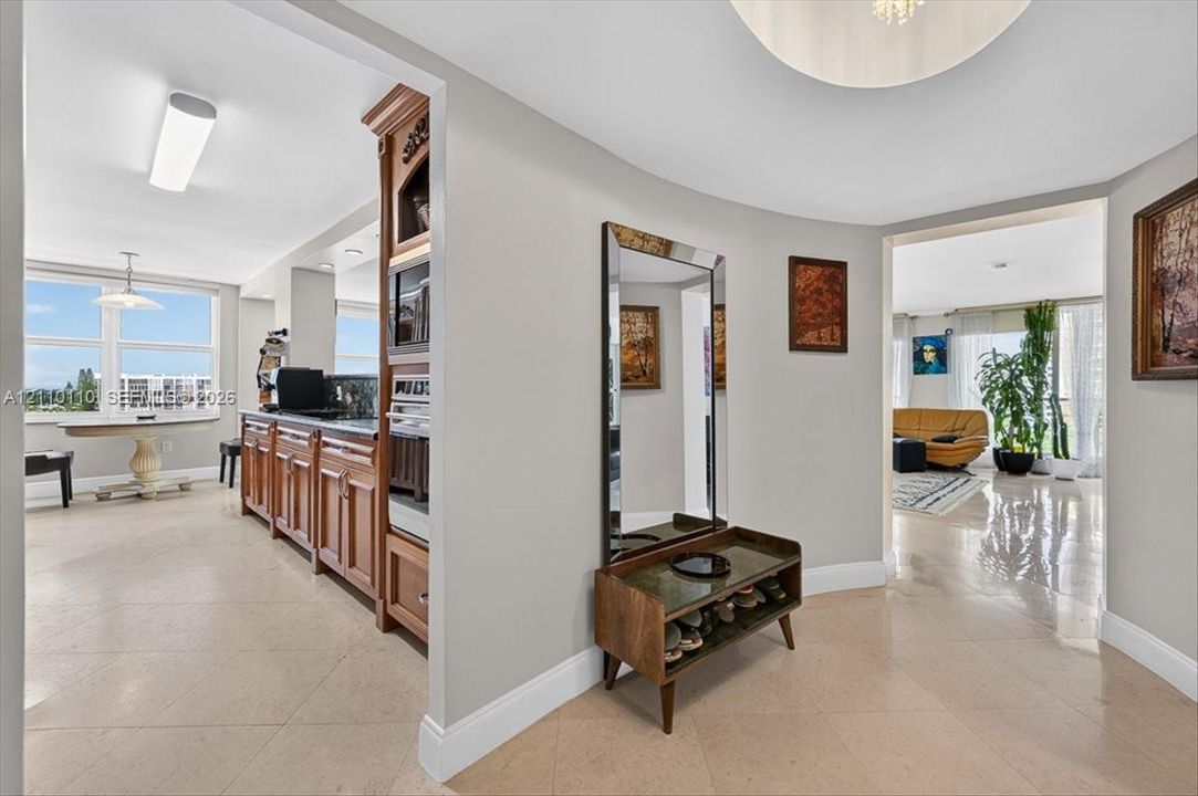 Curved interior wall, polished stone-finish flooring, custom wood cabinetry with integrated built-in oven, and recessed ceiling lighting