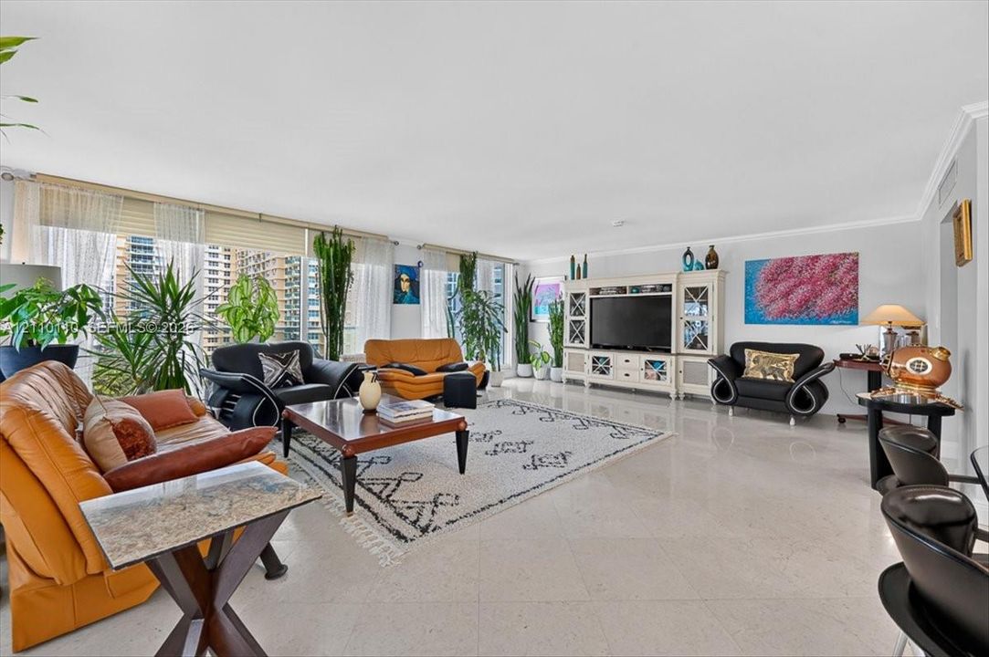 Expansive living area featuring large-format tile flooring, a floor-to-ceiling window wall with integrated blinds, and built-in cabinetry