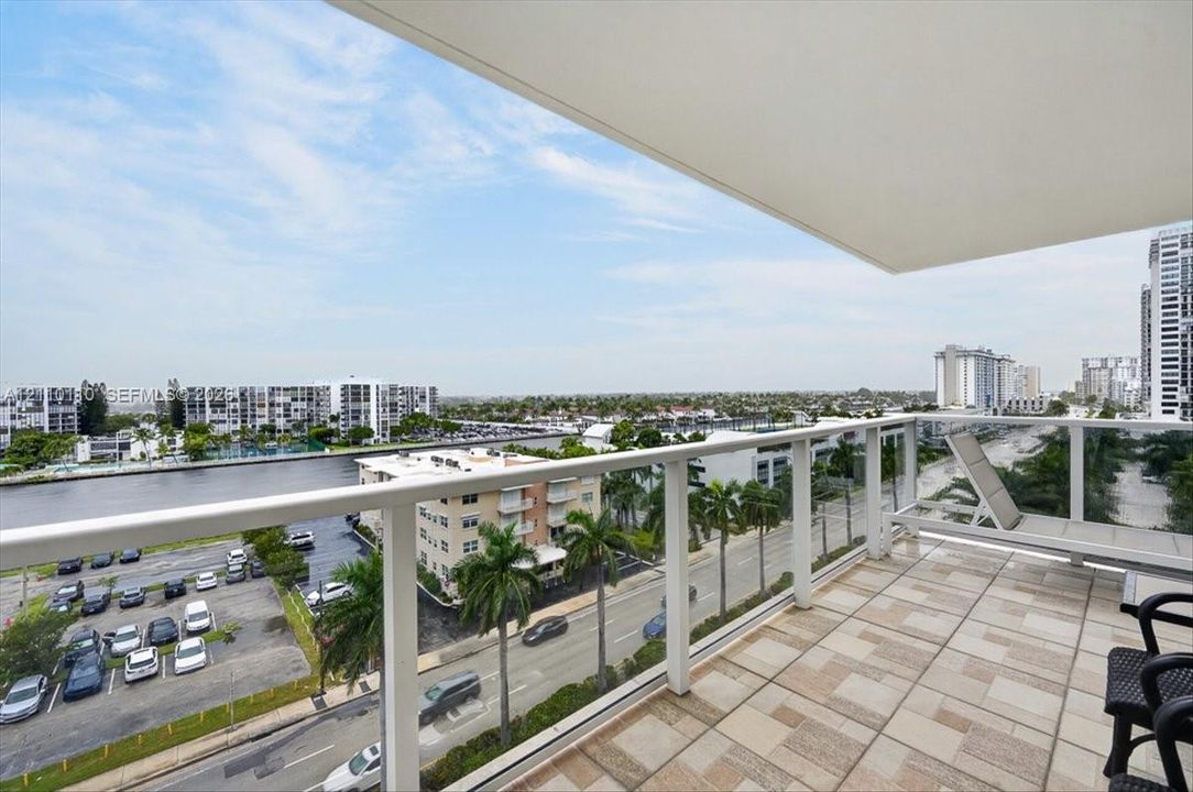 Private balcony featuring a geometric tile floor, white structural railings, and an overhead canopy