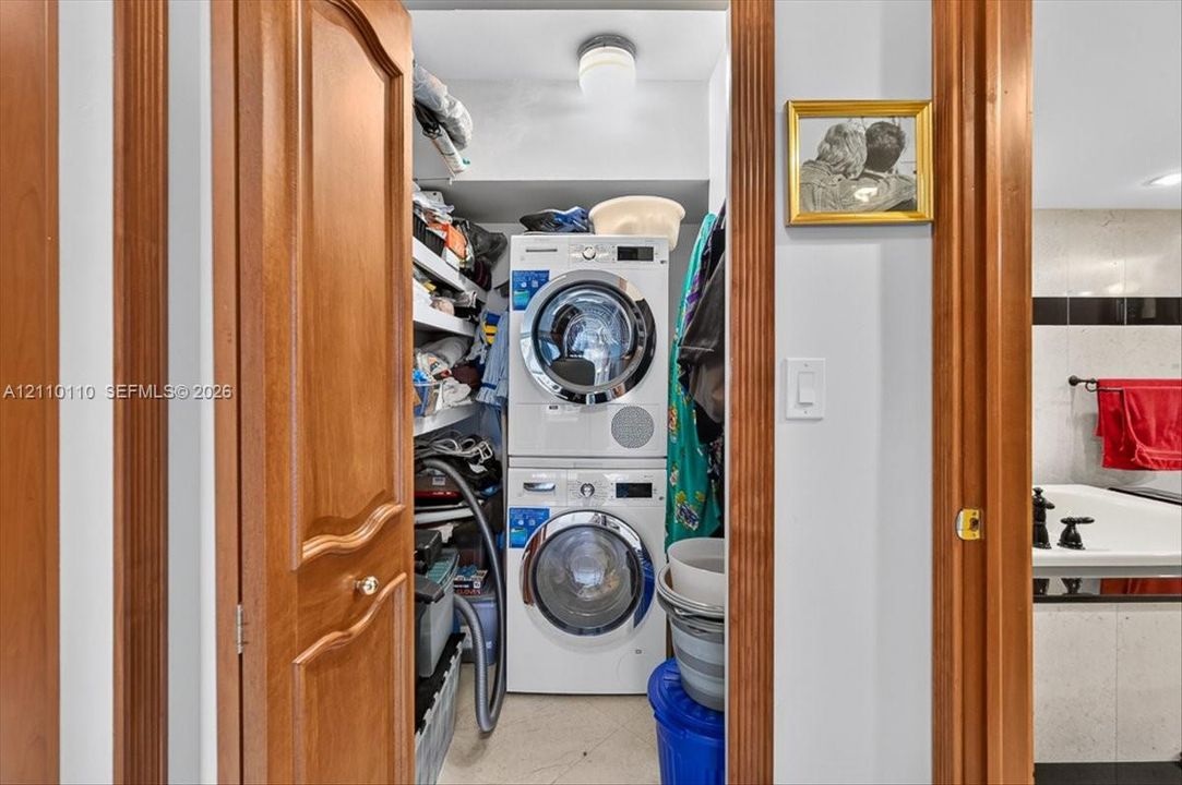 Laundry closet featuring a stackable washer and dryer unit, built-in shelving, and a dome-style ceiling light fixture
