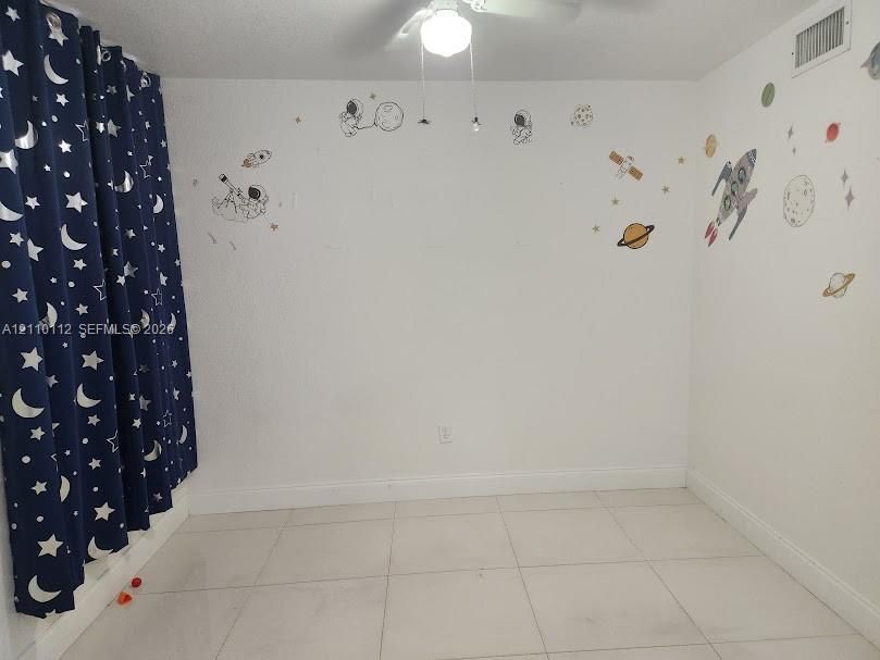 Interior room featuring large-format ceramic tile flooring, neutral white walls, and a ceiling-mounted light fixture