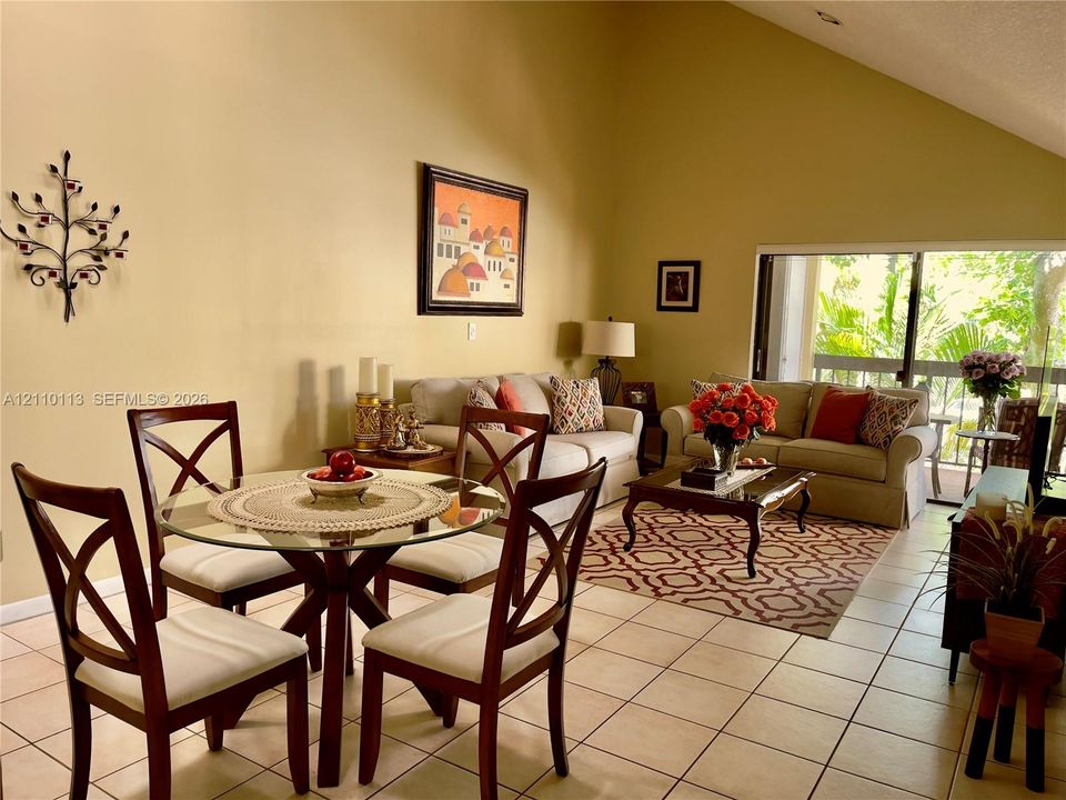 Vaulted ceilings, neutral wall finishes, tile flooring, and sliding glass doors with access to the outdoors