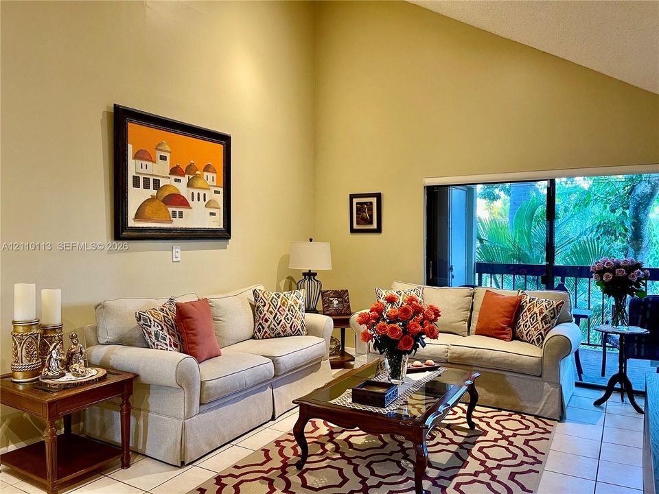 High vaulted ceiling, tile flooring, and oversized sliding glass doors