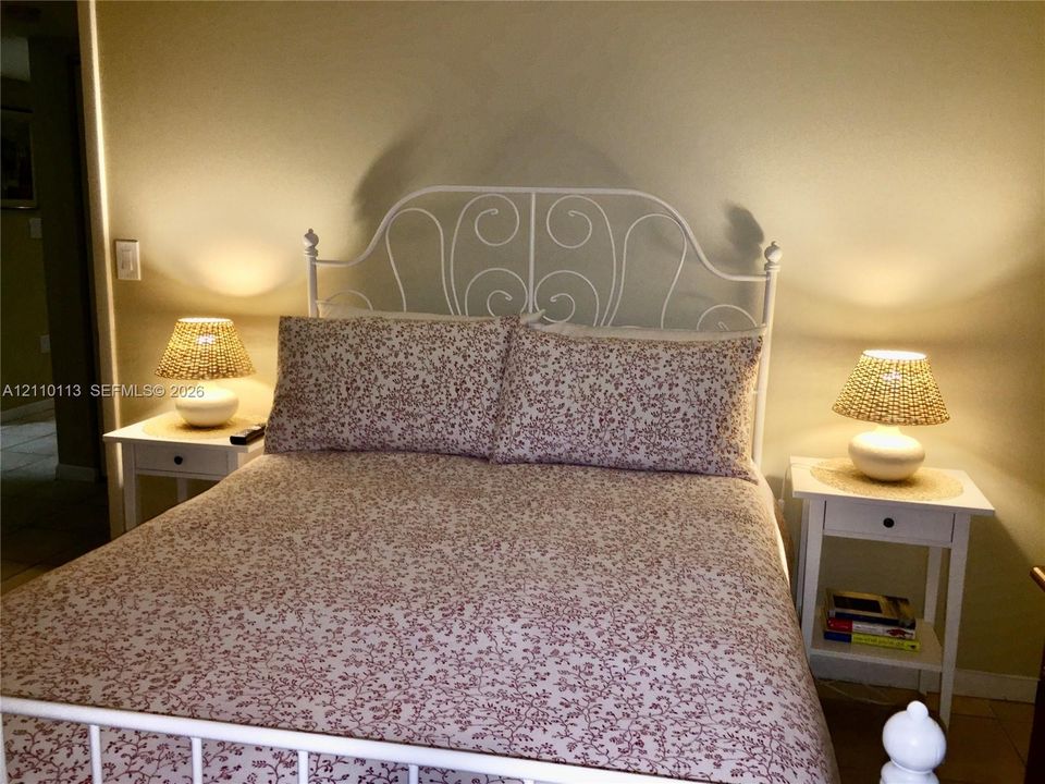 Neutral wall finish and white metal bed frame