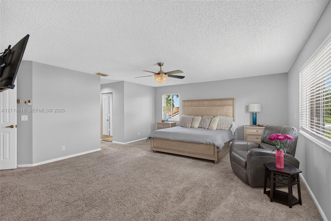 Spacious room featuring neutral carpeting, a central ceiling fan with integrated lighting, and horizontal blinds on the windows
