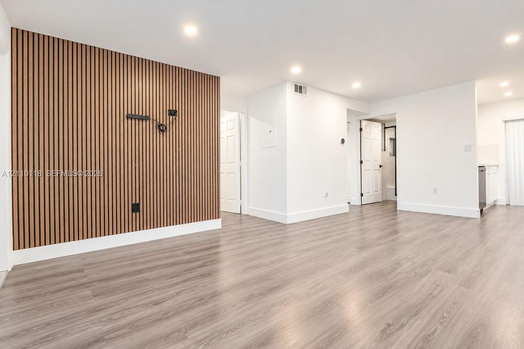 Interior space featuring a vertical wood-slat accent wall, wood-finish flooring, recessed lighting, and multi-panel interior doors