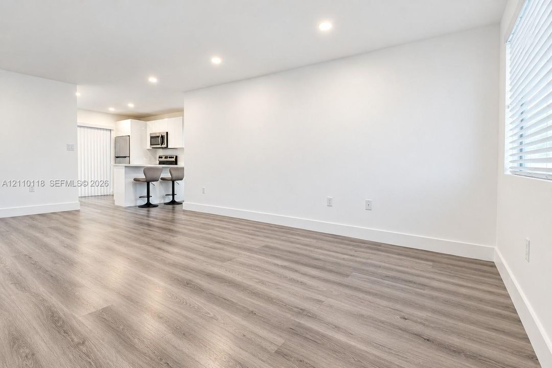 Wood-finish flooring, recessed lighting, white cabinetry, and horizontal window blinds