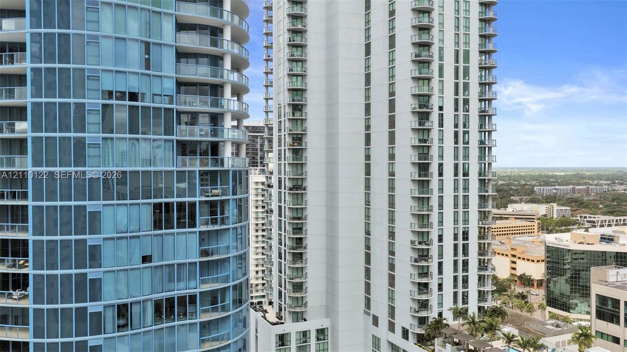 High-rise towers featuring blue tinted glass facades, structured steel balconies, and white architectural cladding