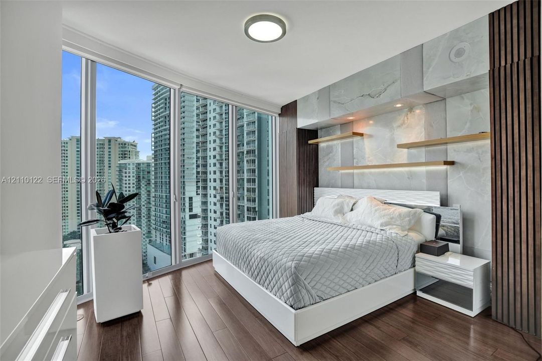 Floor-to-ceiling windows, wood-finish flooring, stone-clad accent wall, custom built-in shelving, and vertical wood-slat wall paneling