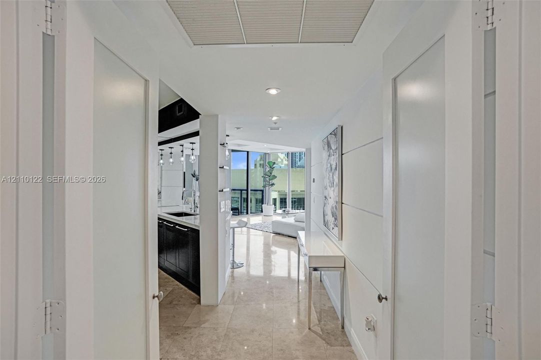 Entryway featuring white double doors with frosted glass insets, polished stone flooring, and recessed ceiling lighting