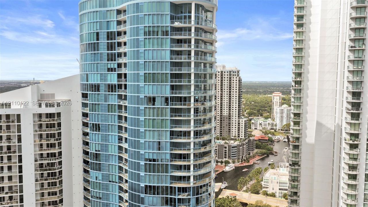 High-rise building featuring a glass facade, curved structural design, and multiple private balconies