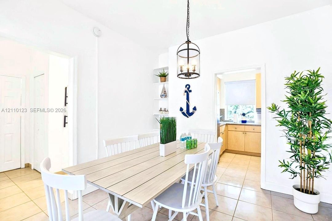 Dining area featuring large-format tile flooring, built-in recessed shelving, and a suspended iron-frame pendant light fixture