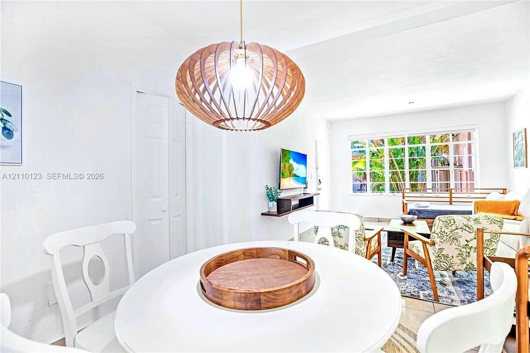 Sculptural wood-slat pendant light fixture, grid-pane windows with outdoor greenery, and light-toned tile flooring
