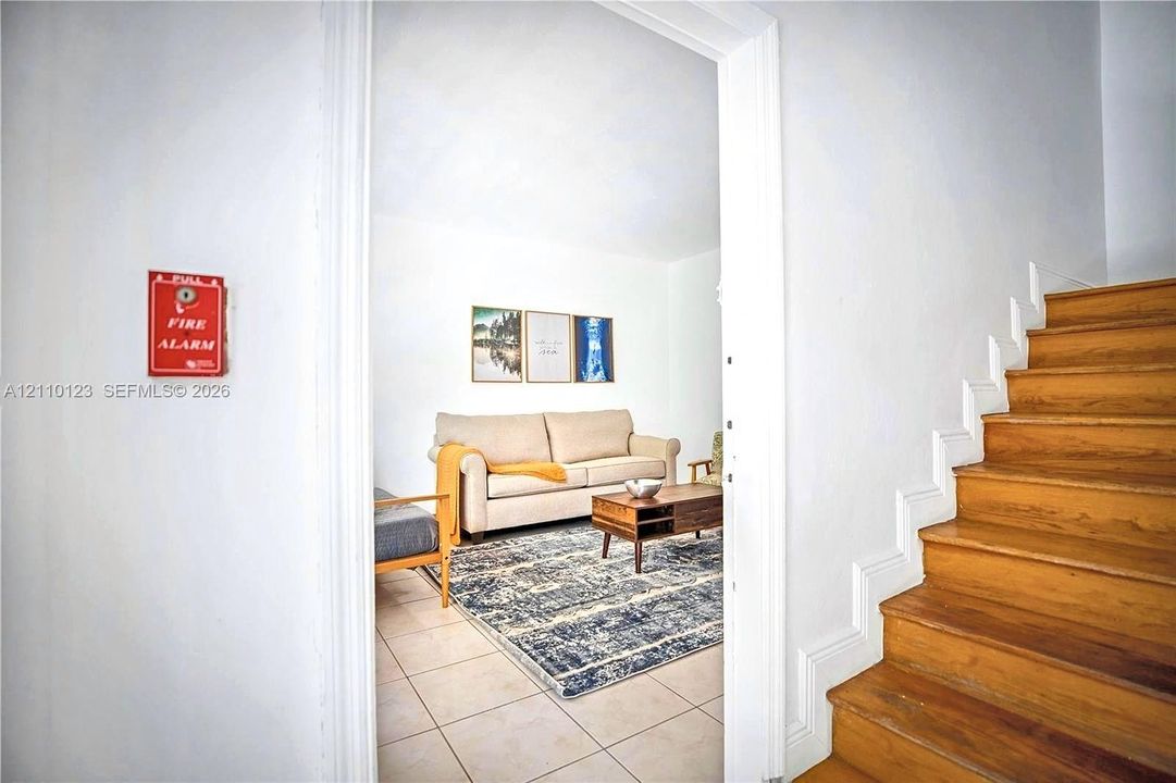 Staircase featuring wood-finish treads and white risers, accompanied by a fire alarm system