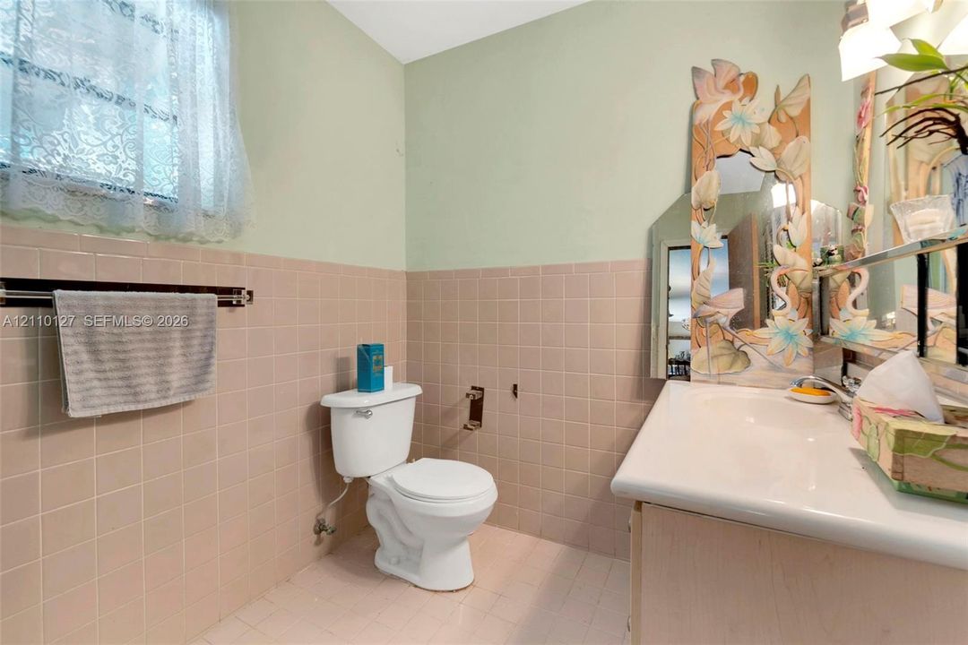 Bathroom featuring a porcelain vanity sink, ceramic wall tiling, and a window