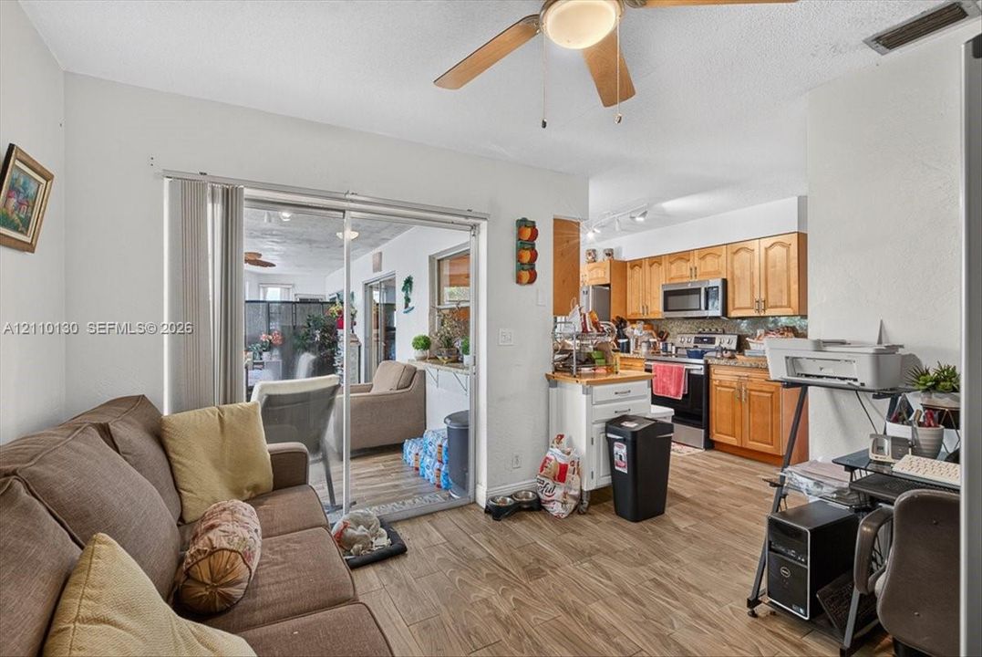 Kitchen featuring wood-finish cabinetry, stainless steel appliances, and wood-finish flooring with sliding glass patio doors